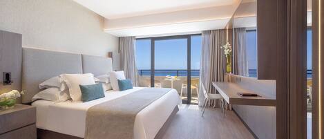 Una camera d'albergo moderna con un letto grande, una scrivania e un balcone vista mare.