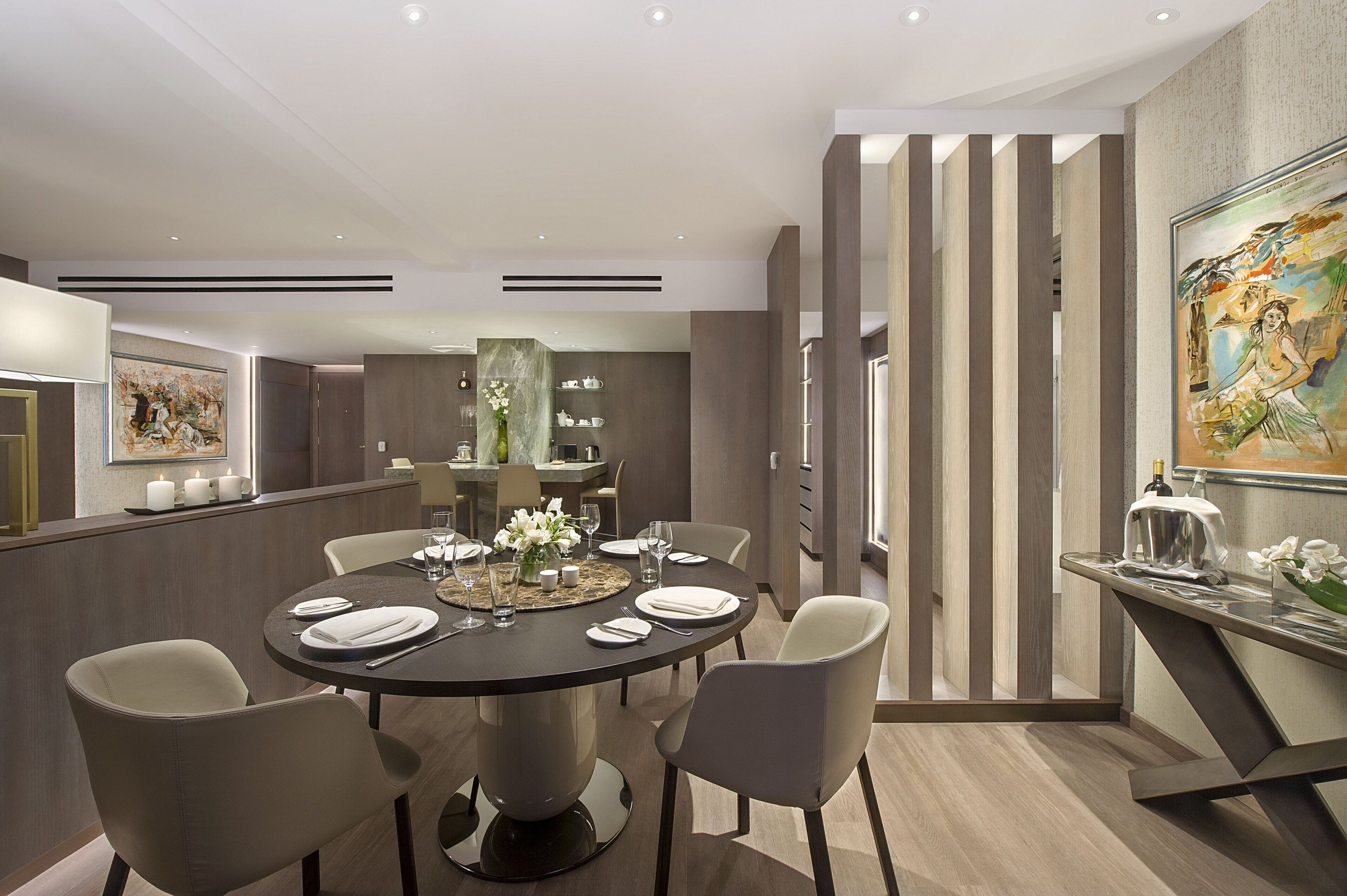 A modern dining area with a round table set for six, surrounded by chairs.