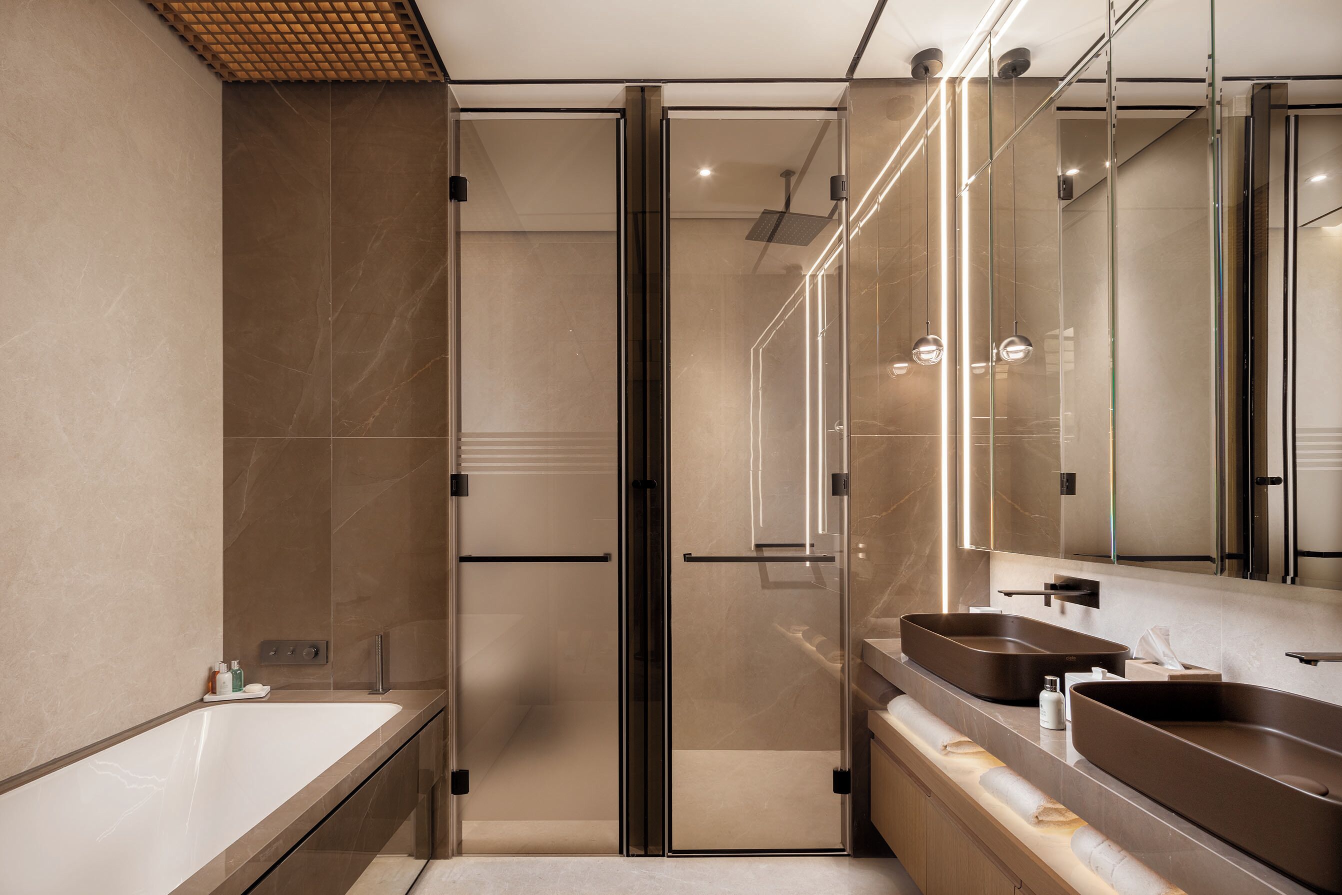 A modern bathroom with a glass-enclosed shower, a large mirror, and two sinks.
