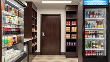 A vending area with various beverage options and snacks, including bottled drinks, cans, and packaged foods.