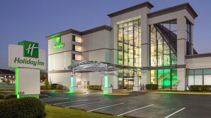 Um hotel Holiday Inn com design moderno, destacando uma entrada ampla em vidro e uma passarela coberta.