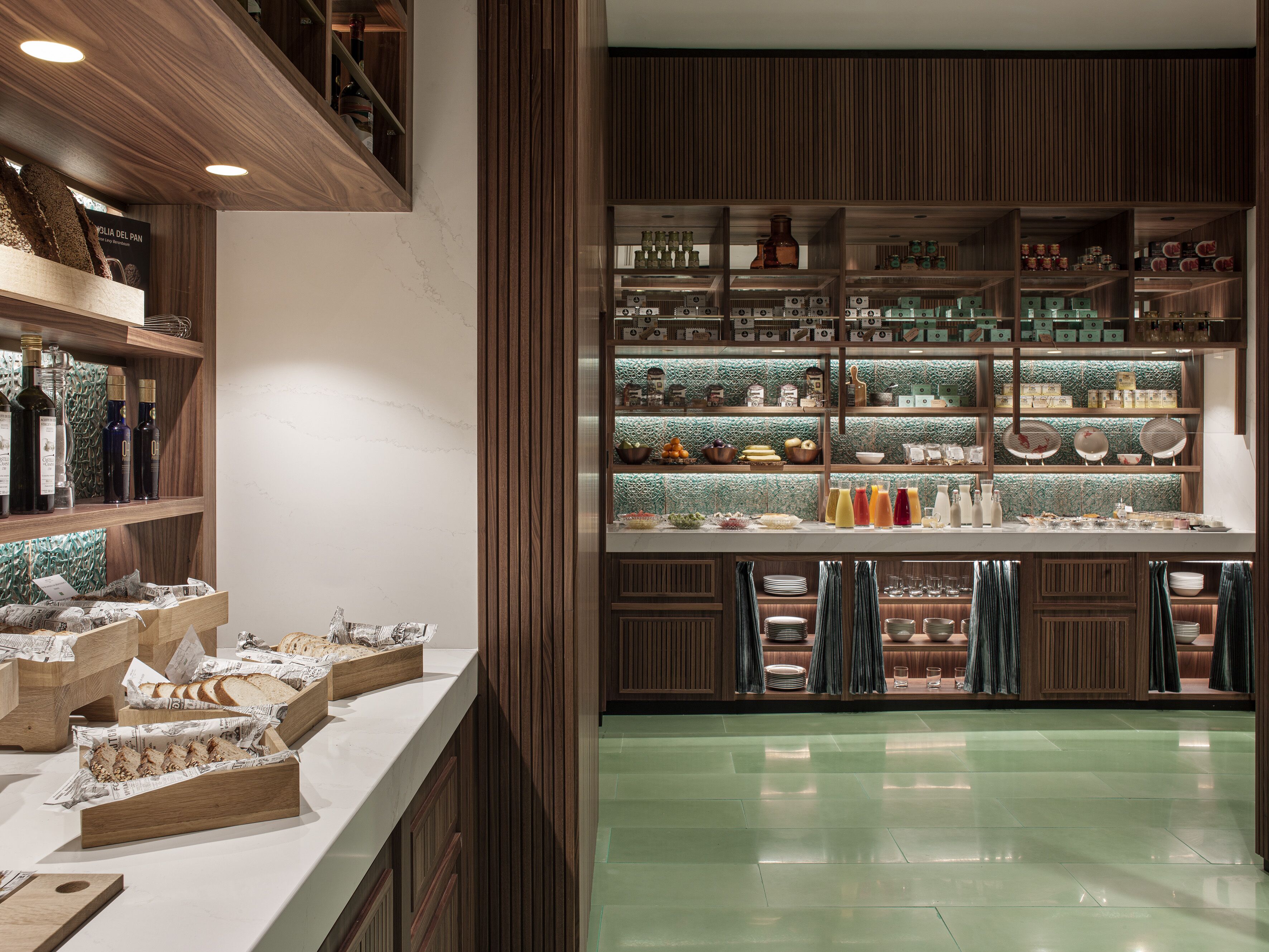 A well-organized kitchen with wooden shelves, a marble countertop, and a green-tiled backsplash.