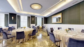 Un salón de conferencias con mesas redondas, sillas y un espejo grande en la pared.