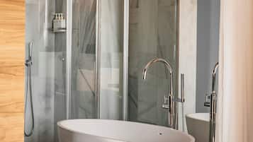 A modern bathroom with a freestanding bathtub, a glass-enclosed shower, and a wooden vanity with toiletries.
