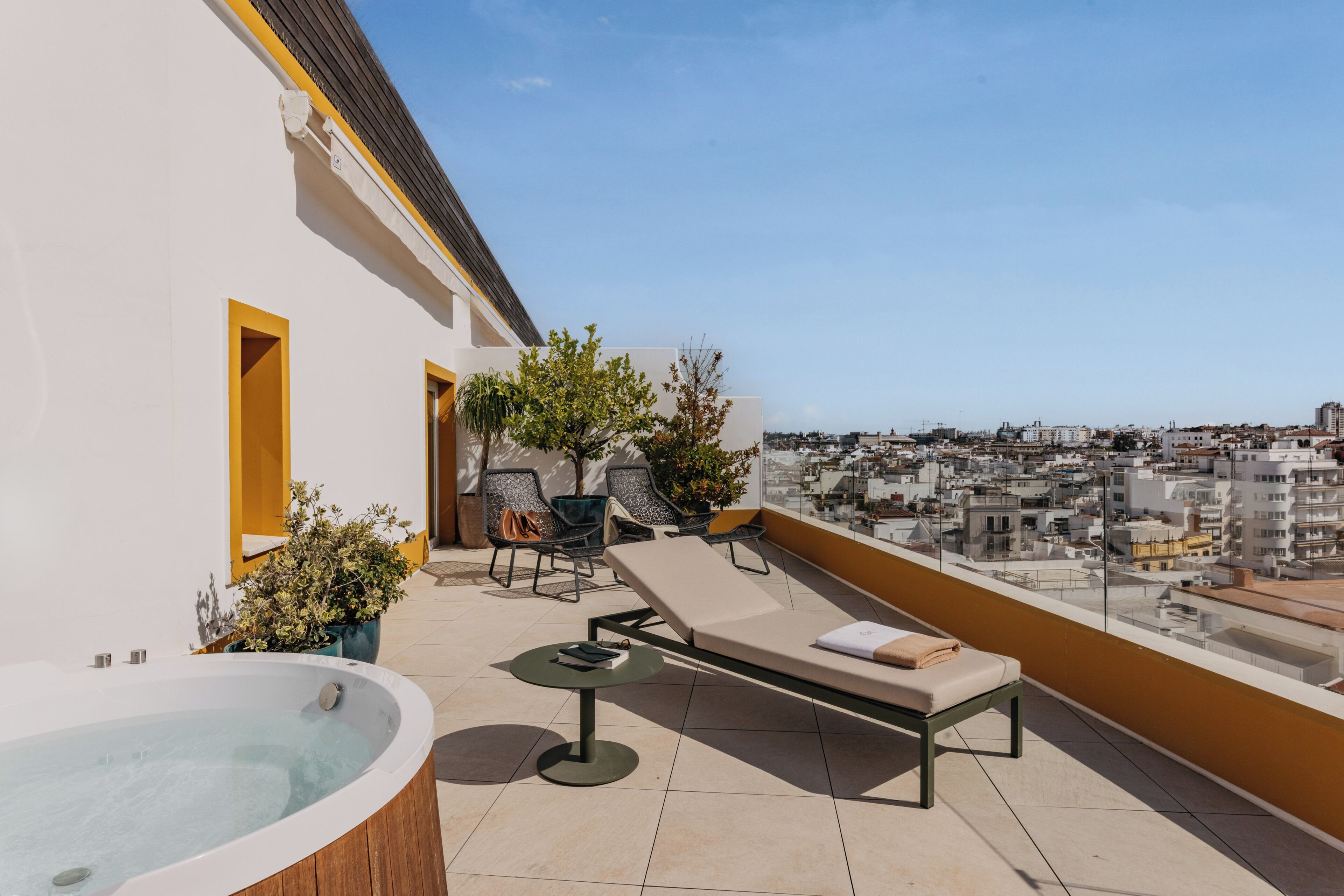 Una terraza en la azotea con hidromasaje, sillones de descanso y plantas en macetas.