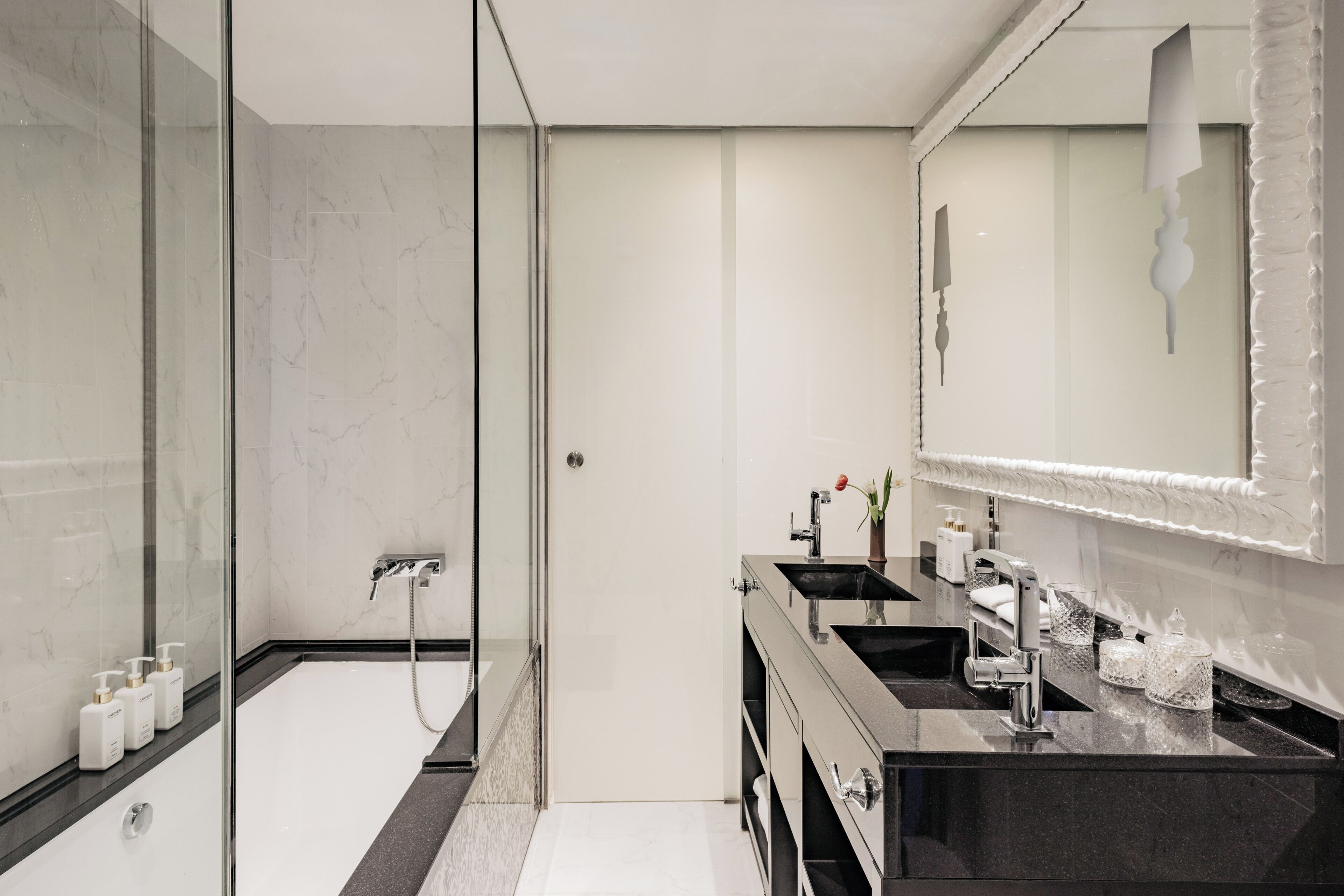 A modern bathroom with a glass shower enclosure, dual sinks, and a large mirror.