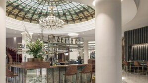 A bar area with a glass enclosure, a chandelier, and a seating arrangement.