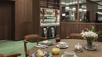 Un comedor con muebles de madera, una mesa dispuesta con platos, tazas y un jarrón de flores.