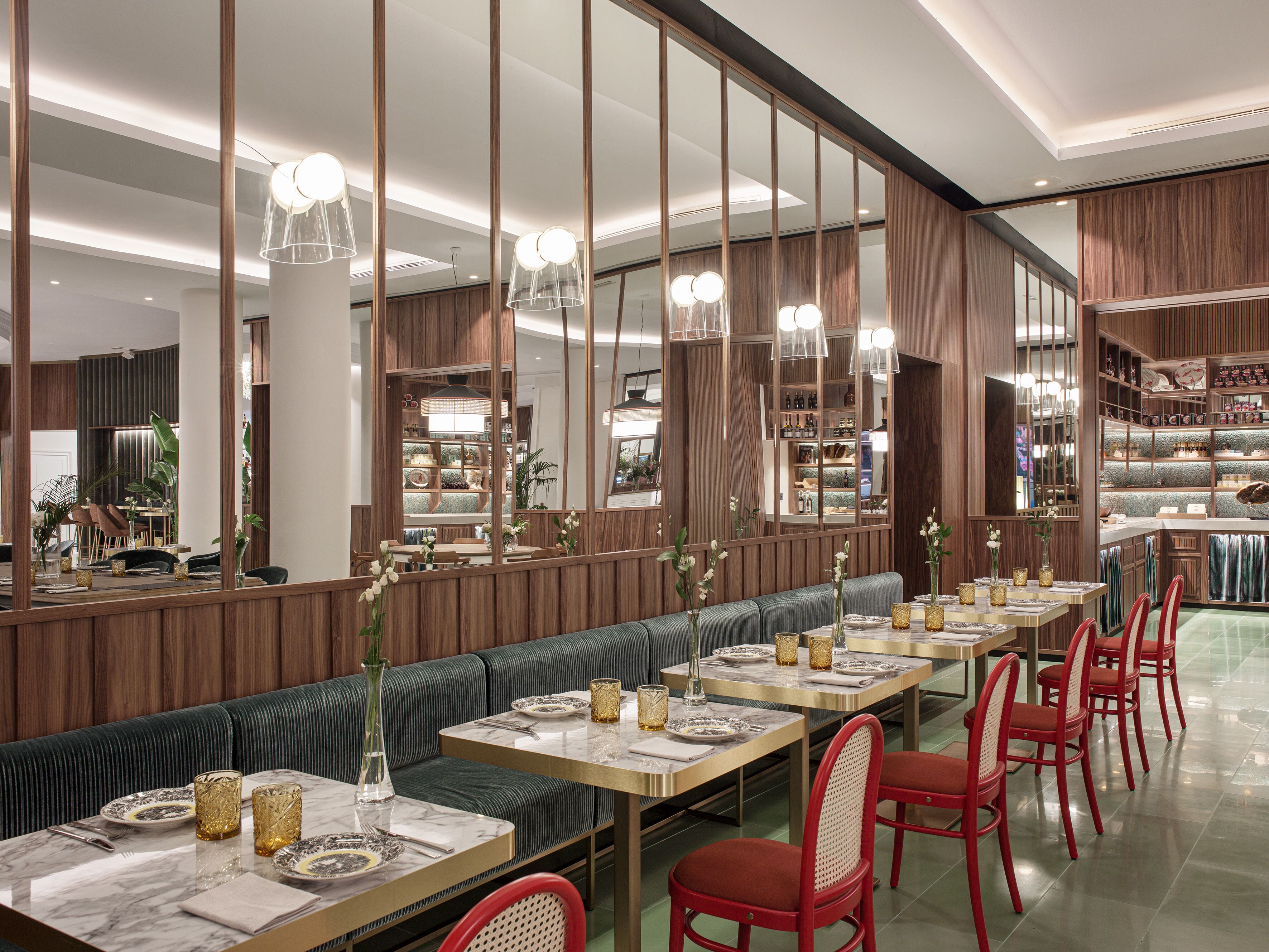 A modern restaurant with a long counter, booths, and red chairs.