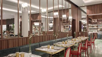 A modern restaurant with a long counter, booths, and red chairs.