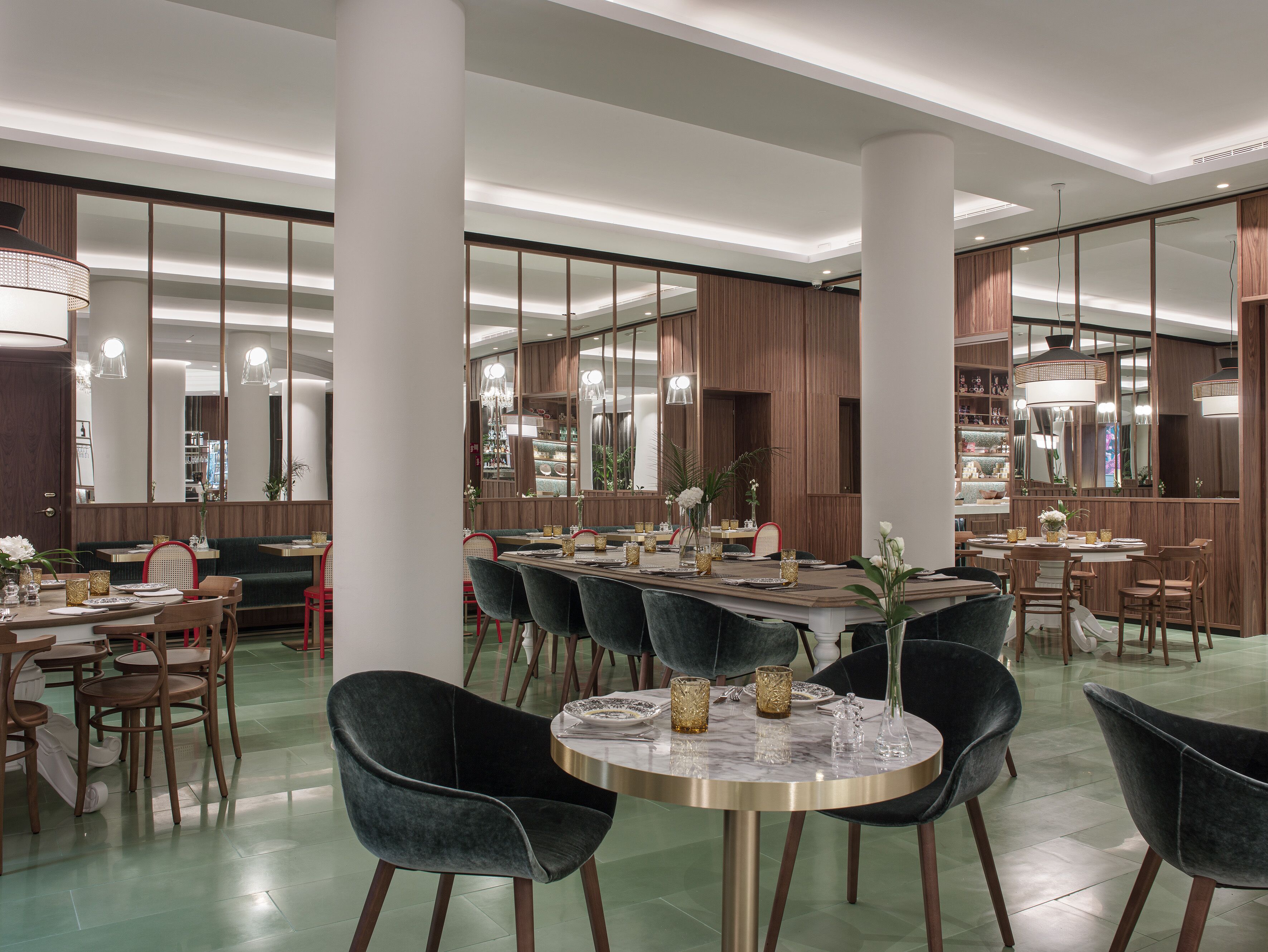 A spacious dining area with high ceilings, large mirrors, and modern furniture.
