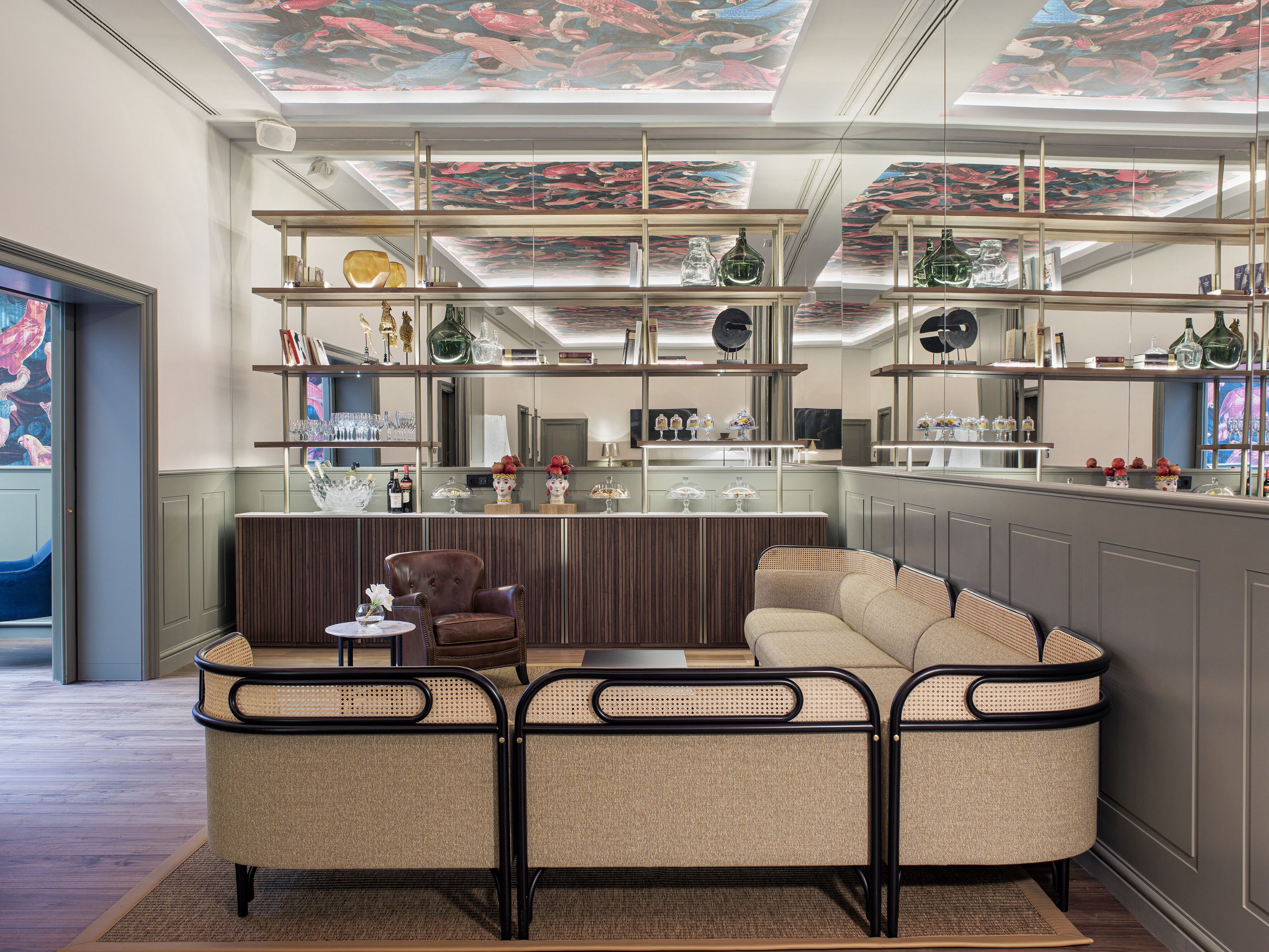 A modern interior with a sofa, chairs, and a bar area with shelves.