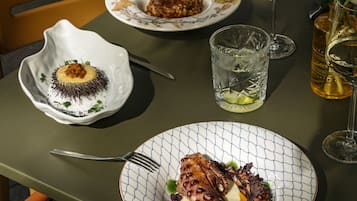 Una mesa dispuesta con platos de comida, copas de vino y un florero con flores.