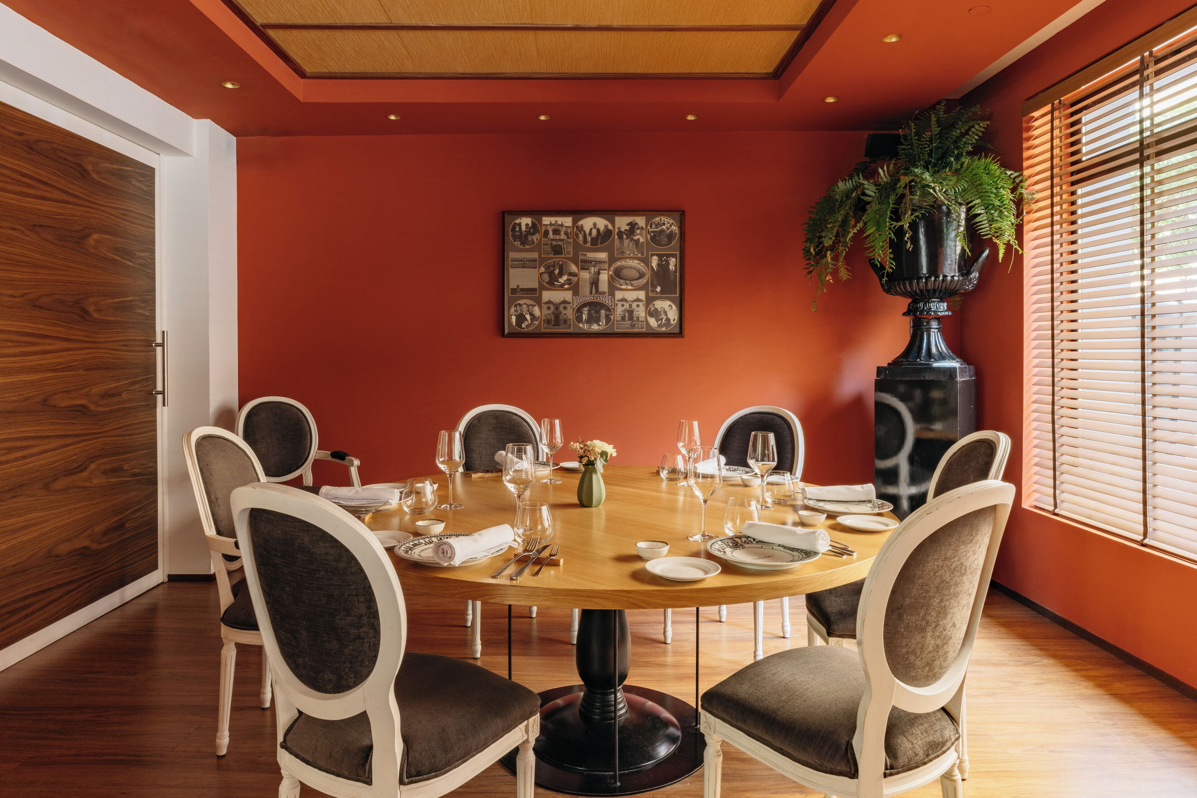 Une salle à manger avec une table ronde dressée pour six personnes, entourée de six chaises.