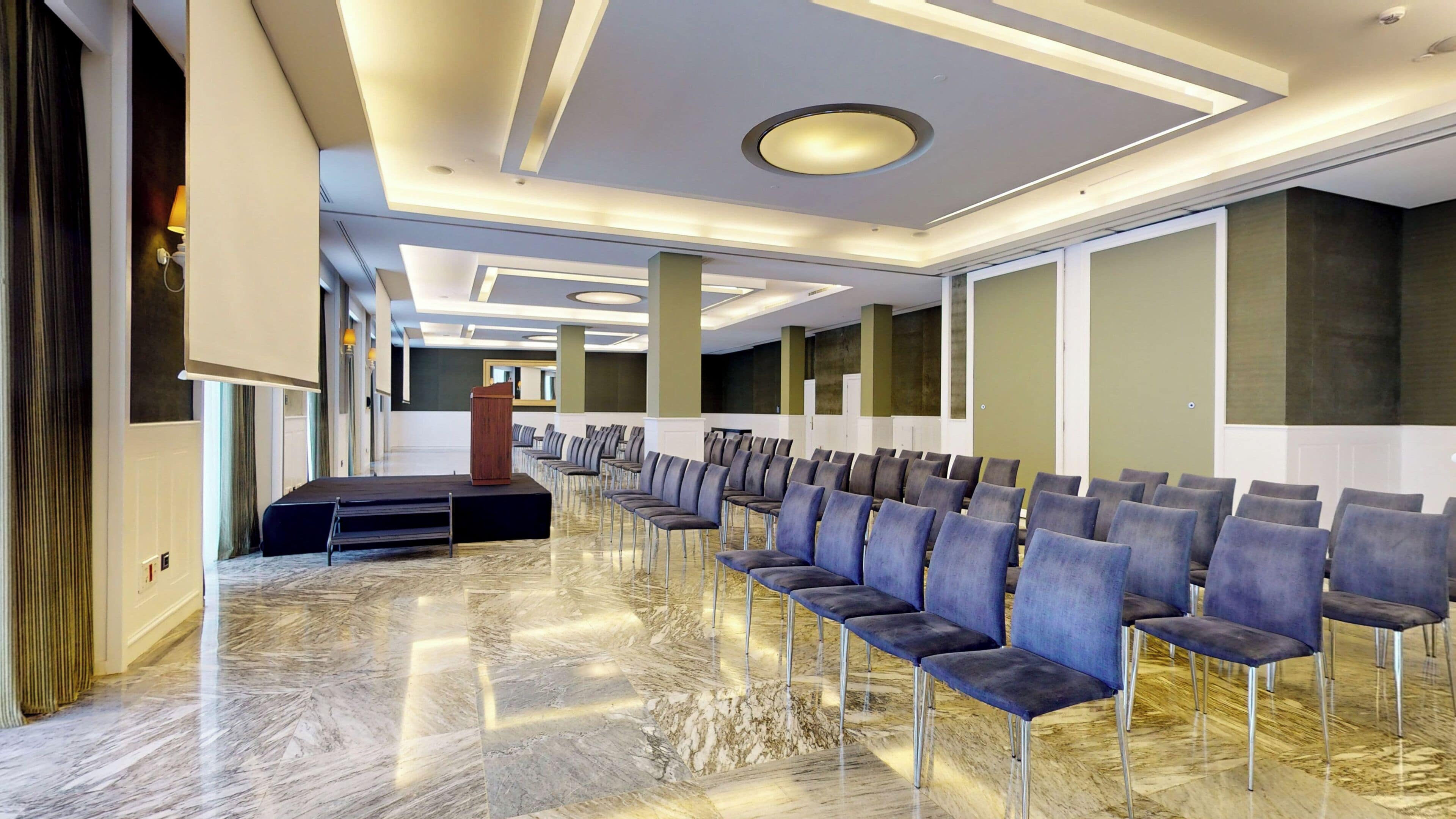 Un salón de conferencias con filas de sillas, un atril y un suelo de mármol.