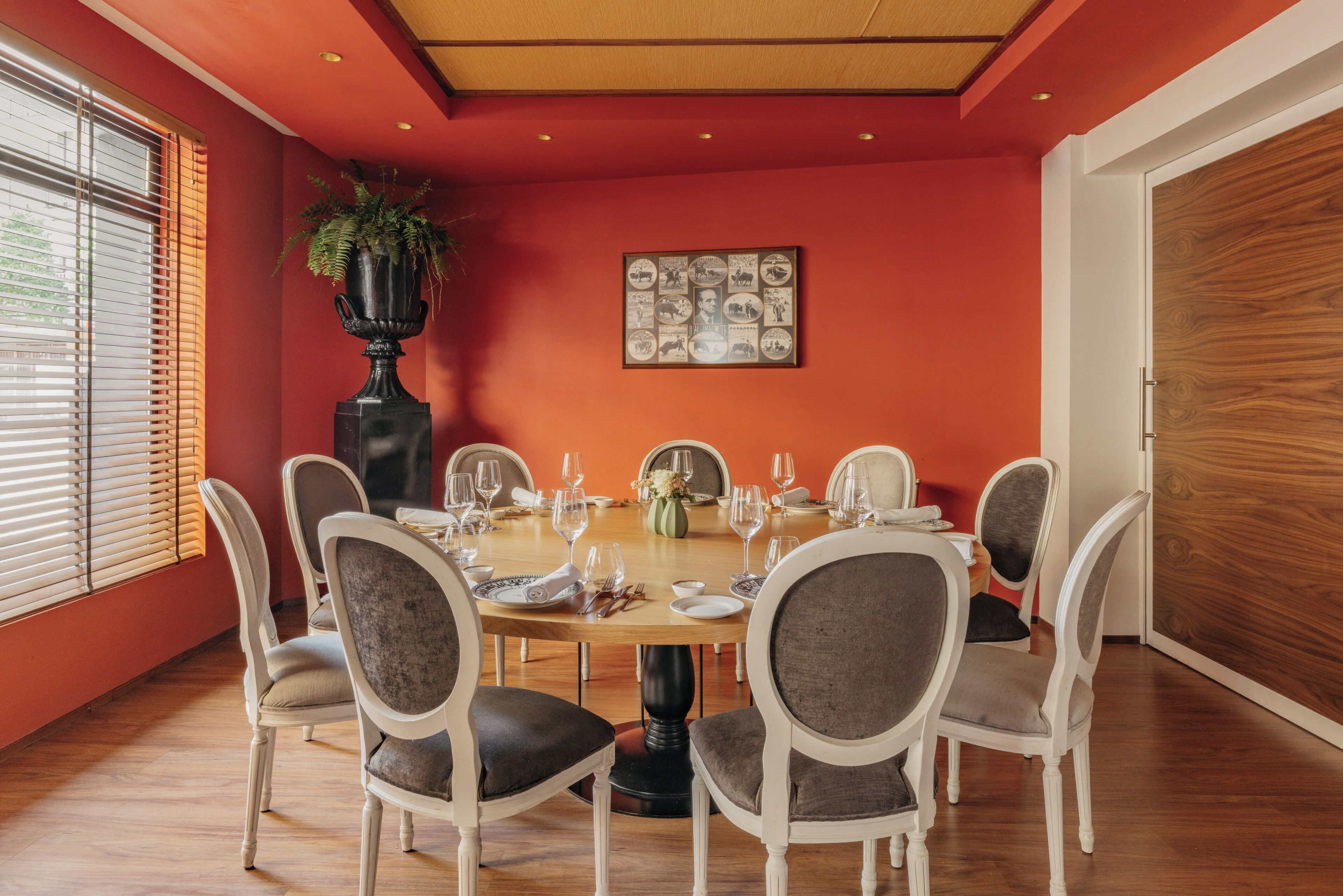 A dining room with a round table set for six, surrounded by six chairs.