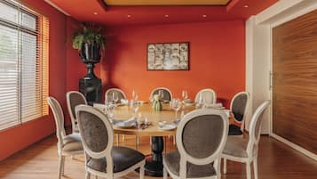 A dining room with a round table set for six, surrounded by six chairs.
