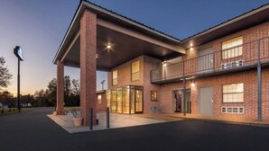 A two-story building with a brick facade, large windows, and a covered entrance area.