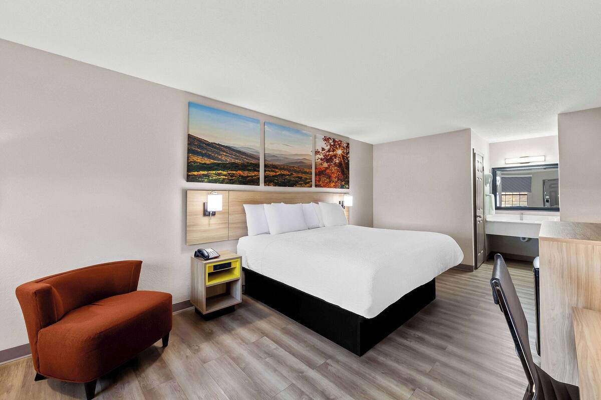 Une chambre d’hôtel moderne équipée d’un grand lit, d’un bureau, d’une chaise et d’une table de chevet.