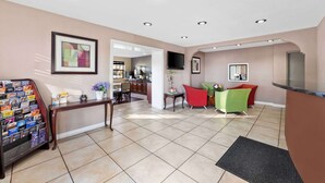 A spacious living area with a kitchen in the background, a dining table with chairs, and a TV mounted on the wall.