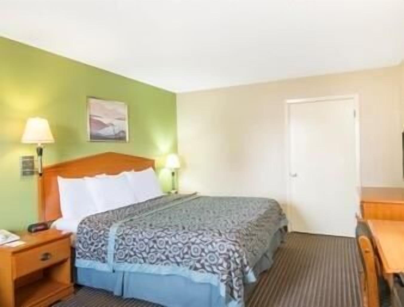 Een hotelkamer met een bed, nachtkastjes, een bureau en een stoel.