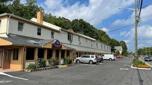 Un edificio de dos pisos con un letrero que dice Whitney Inn & Suites. Hay coches estacionados al frente y un cielo despejado.