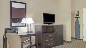 Una habitación de hotel con escritorio, silla, televisor y espejo.