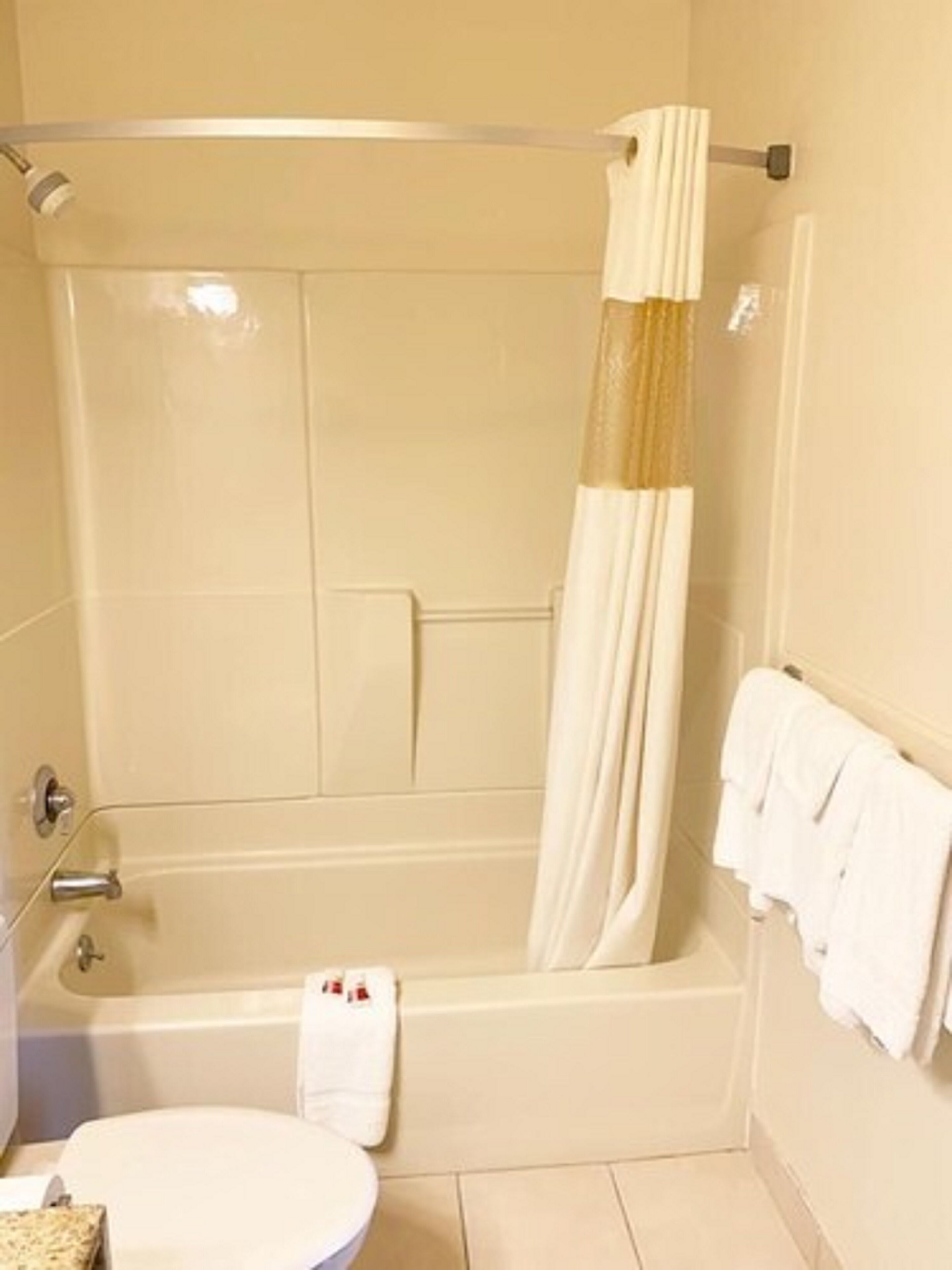 Un baño con bañera, inodoro y cortina de ducha.