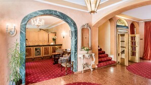 A grand lobby with a marble archway, a chandelier, and a staircase with red steps. - Romantik Hotel Bülow Residenz (Dresden)