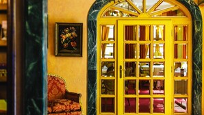 A yellow door with glass panels, a red patterned chair, and a painting on the wall. - Romantik Hotel Bülow Residenz (Dresden)
