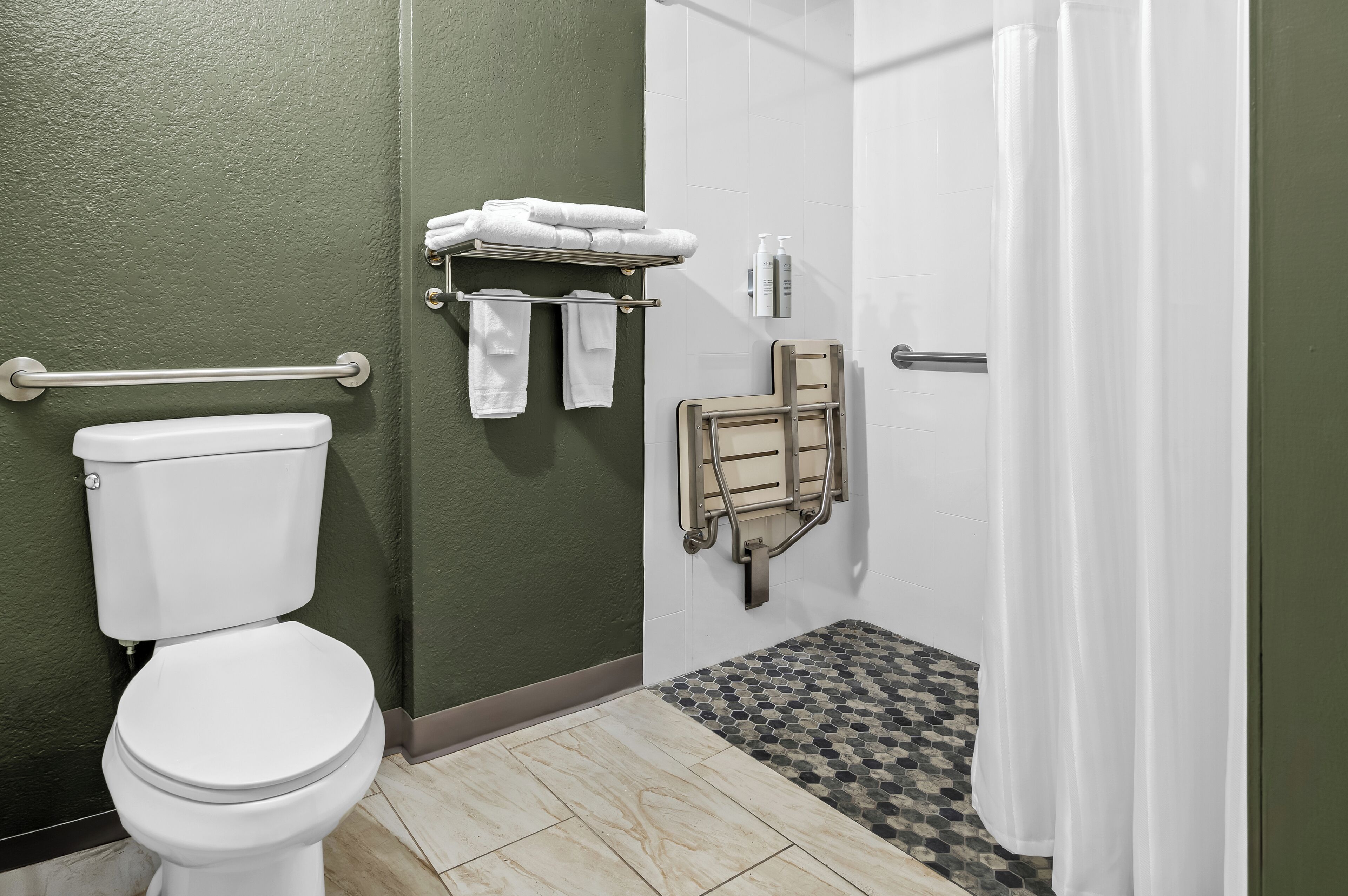 A bathroom with a toilet, a shower, and a grab bar.