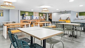 Una cafetería moderna con varias mesas y sillas, una barra con alimentos y un letrero que dice "Delight".