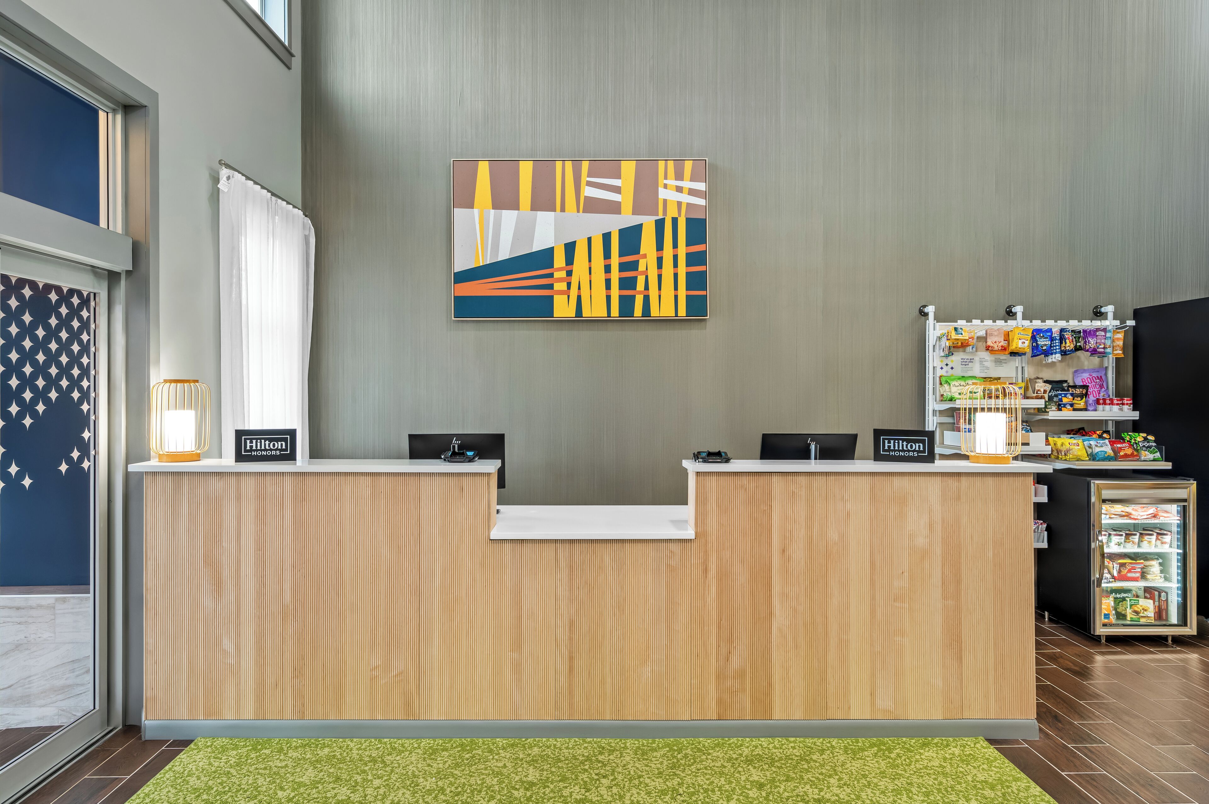 Una recepción de hotel con diseño moderno, una obra de arte en la pared y una máquina expendedora de aperitivos.