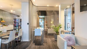 Een moderne eethoek met een houten tafel, witte stoelen en een glazen scheidingswand.