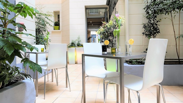 Un patio intérieur avec une table et des chaises, entouré de plantes en pot et doté d’un aménagement intérieur moderne.
