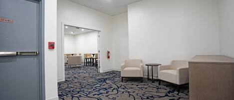 Um saguão de hotel com piso coberto por carpete, balcão de recepção e área de estar.