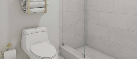 Un baño moderno con inodoro, cabina de ducha de vidrio y perchero para toallas.