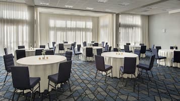 A conference room with round tables, chairs, and a patterned carpet.