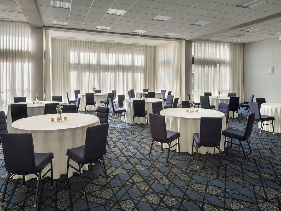 A conference room with round tables, chairs, and a patterned carpet.