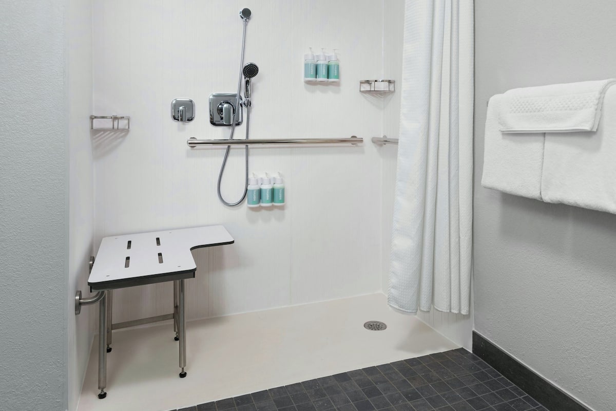 A bathroom with a shower, a sink with a mirror, and a towel rack.