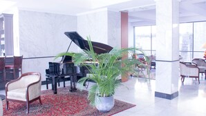 A spacious lobby with a grand piano, comfortable seating, a large potted plant, and a view through large windows. - ibis Périgueux Centre (Périgueux)