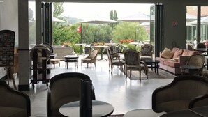 An indoor seating area with tables and chairs, a sofa, and a view of the outdoors. - ibis Périgueux Centre (Périgueux)