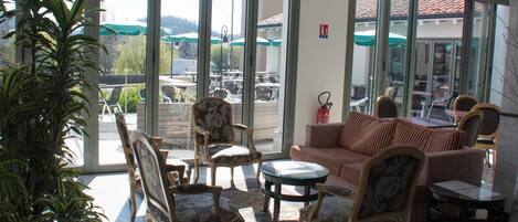 A spacious indoor area with large windows, a sofa, chairs, and a small table.