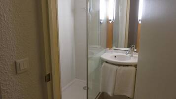 Une salle de bain avec une douche à parois de verre, un lavabo blanc et un miroir.