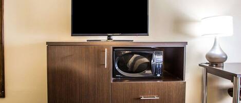 Habitación de hotel con un mueble de madera que contiene un microondas, un televisor y una lámpara.