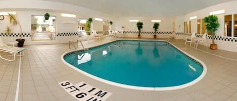 Piscina interior com profundidade de 1,10 metros, rodeada por piso de azulejos brancos e padrões de parede quadriculados.