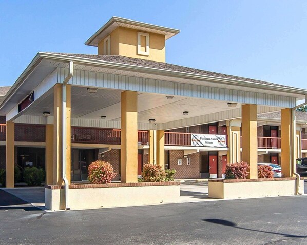 Een motel met overdekte parkeerplaats, meerdere kamers en een bord met de vermelding 'Platinum Award Winner'.