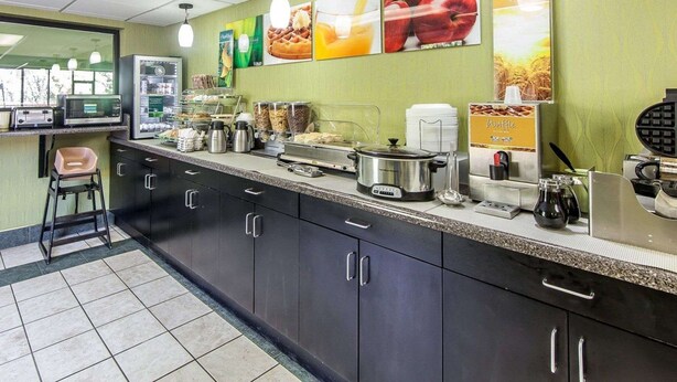 A breakfast bar with various food items and appliances, including a waffle maker and coffee machine. - Quality Inn Sweetwater West (Sweetwater)