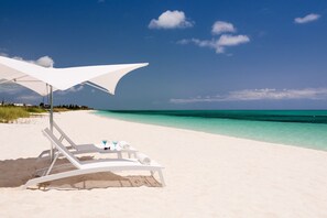 Am Strand, weißer Sandstrand, Liegestühle, Sonnenschirme