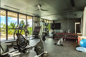 Un gimnasio con equipo de cardio, máquinas de pesas y mancuernas.